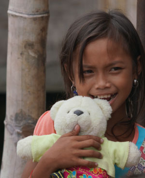 Child from the Philippines holding a teddy bear and smiling