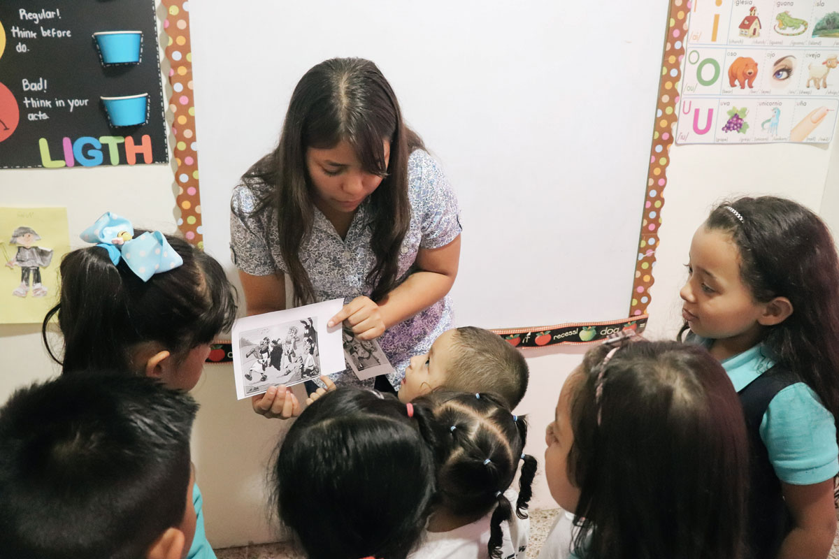 Mayra showing a book to the kids