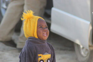 Laughing toddler in Zimbabwe wearing a yellow hat