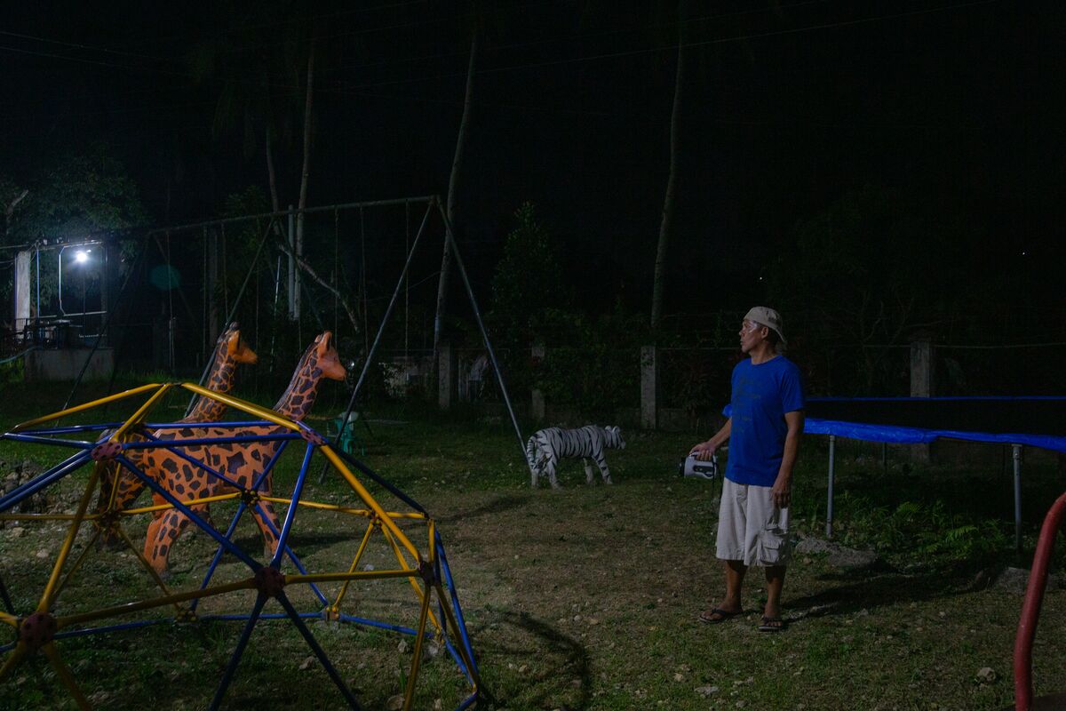A man with a flashlight patrols a children's playground.