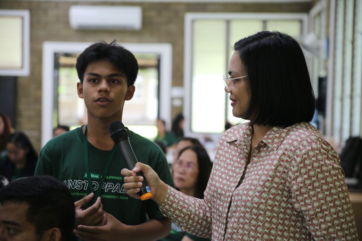 Speaker Micah Abalos holds the mic for a young man answering her questions