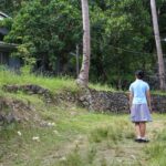 A teen girl walks through the lush green campus of happy horizons children's ranch